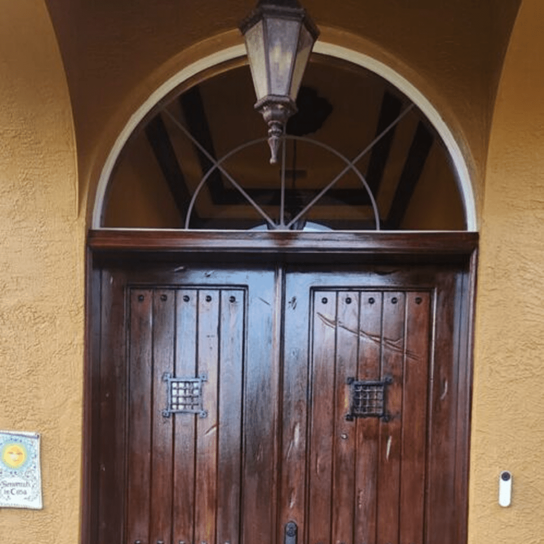 Brown arched wooden double doors with lantern